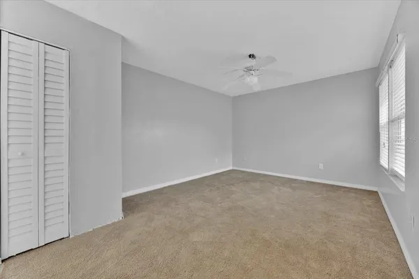 an empty room with windows and fan