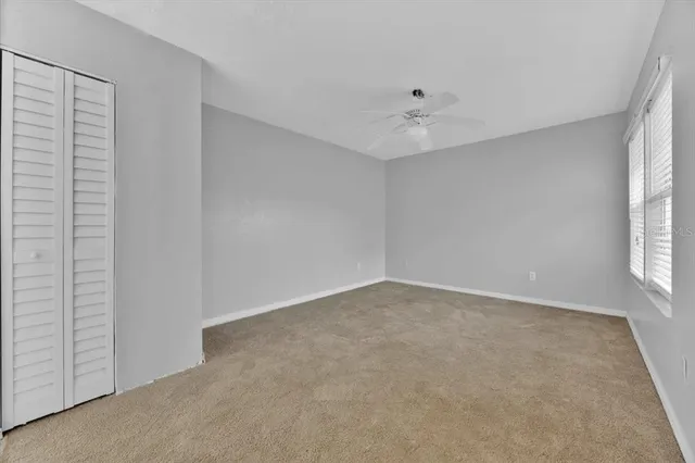 an empty room with windows and fan