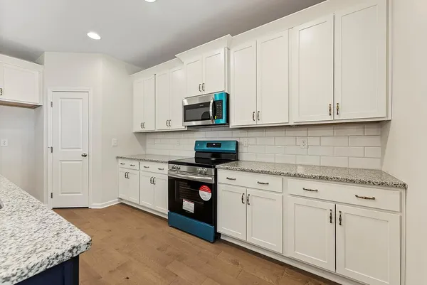 a kitchen with granite countertop white cabinets and stainless steel appliances