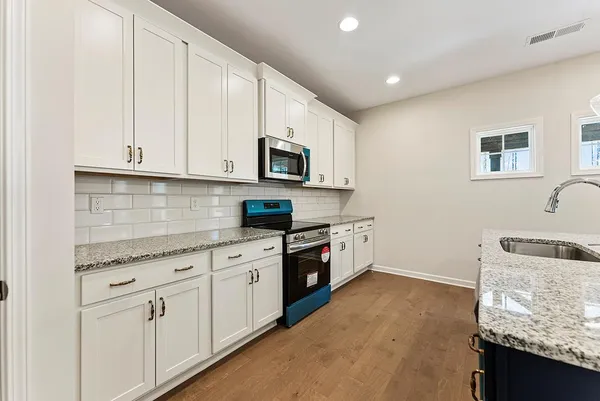 a kitchen with granite countertop white cabinets and black stainless steel appliances