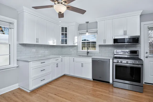 a kitchen with stainless steel appliances white cabinets and a stove a oven with wooden floors