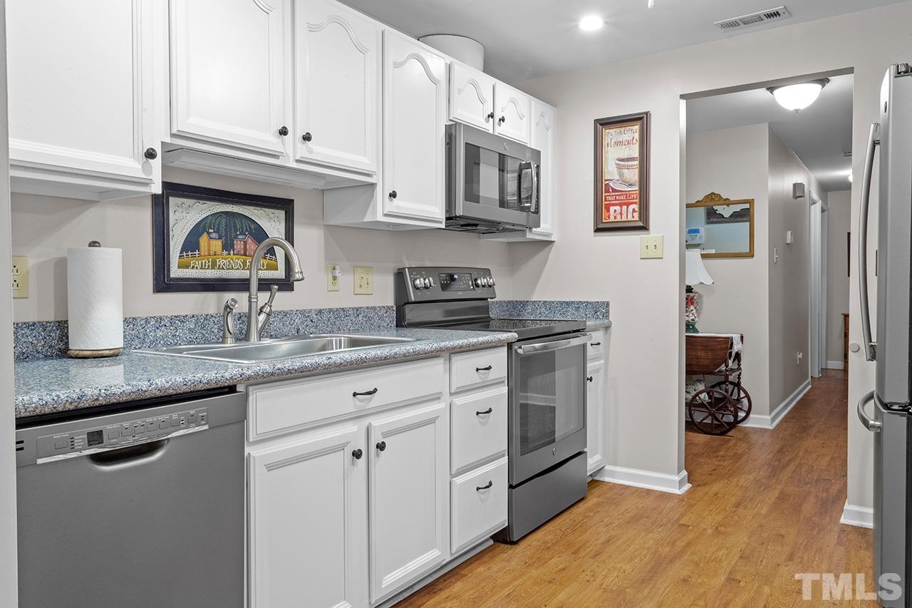 6921 Chamonix Place Raleigh, NC 27613 - Photo 6 of 30 a kitchen with stainless steel appliances granite countertop a sink stove and cabinets