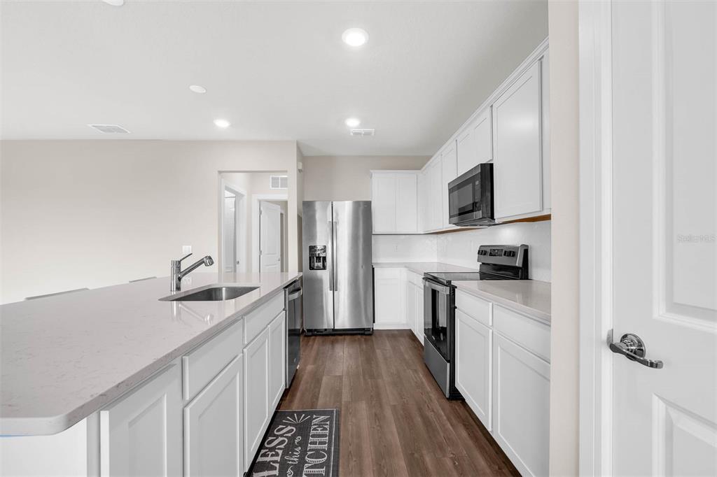 7367 Catania Loop Clermont, FL 34714 - Photo 7 of 58 a kitchen with kitchen island granite countertop a sink stove refrigerator and cabinets