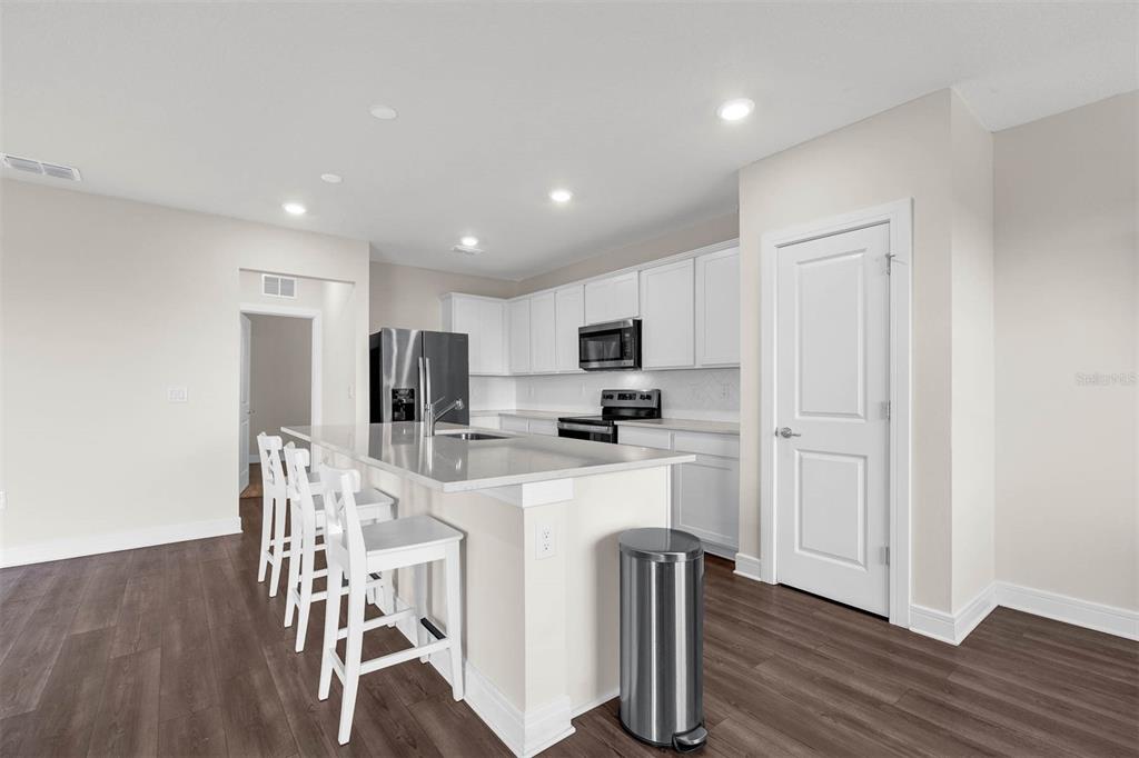 7367 Catania Loop Clermont, FL 34714 - Photo 8 of 58 a kitchen with stainless steel appliances a dining table chairs refrigerator and cabinets