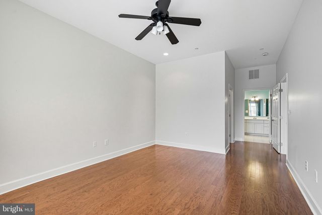 a view of a hallway with wooden floor and a chandelier fan