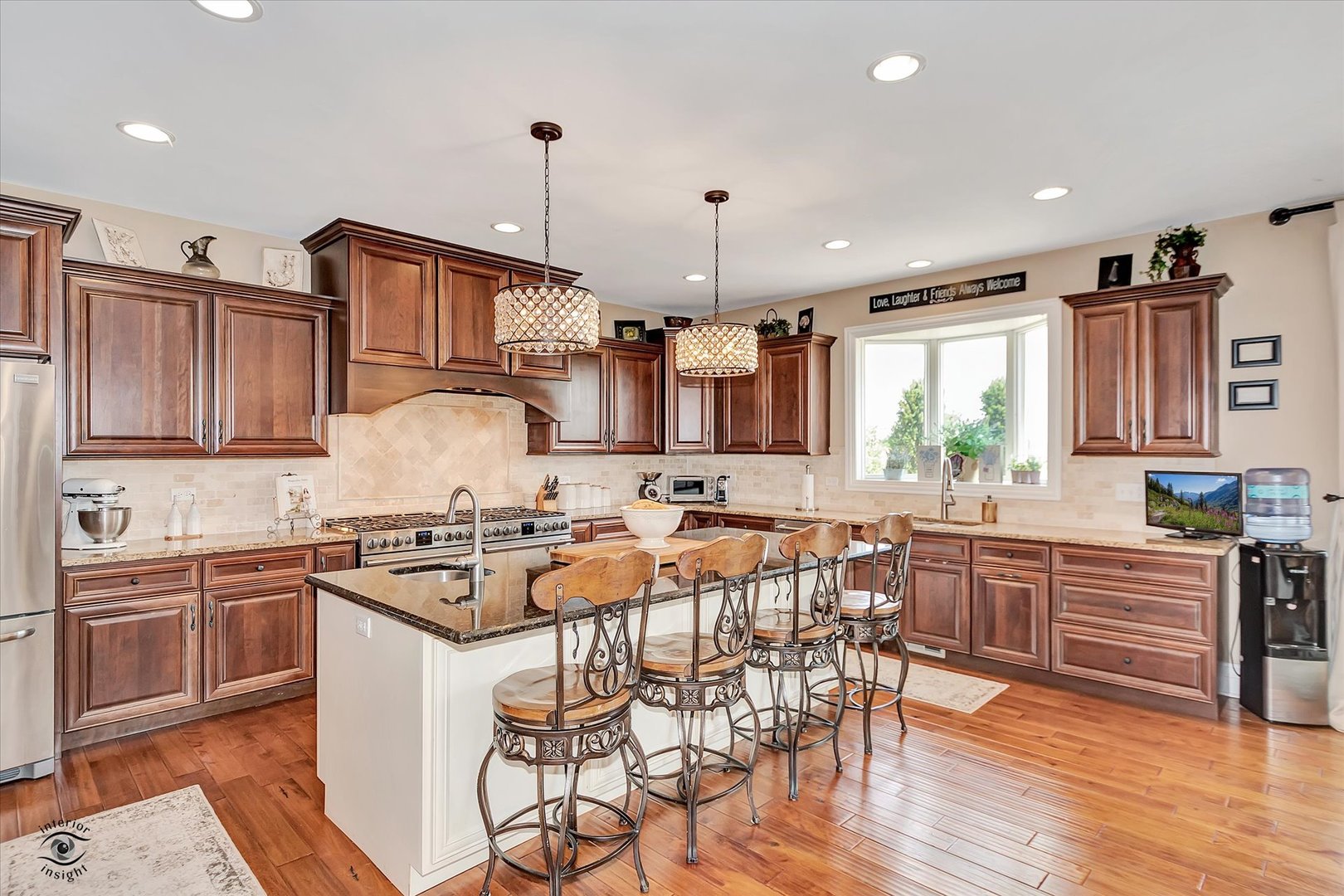 23933 Roberts Street Manhattan, IL 60442 - Photo 5 of 26 a kitchen with stainless steel appliances granite countertop a stove top oven a sink a dining table and chairs with wooden floor
