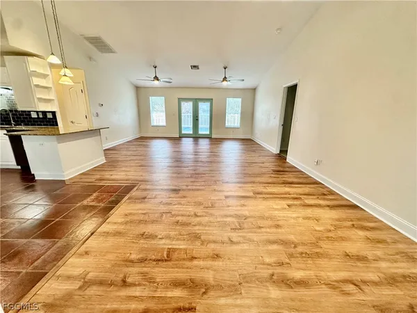 a view of empty room with wooden floor and fan