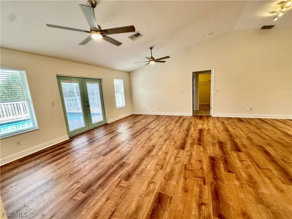 an empty room with wooden floor and ceiling fan