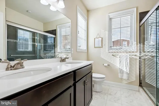a bathroom with a granite countertop sink a toilet a mirror and shower