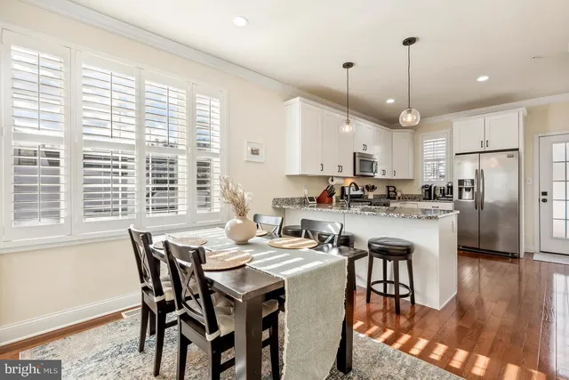 a kitchen with stainless steel appliances granite countertop a stove a refrigerator a kitchen island a table and chairs