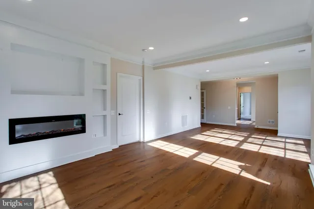 a view of a livingroom with wooden floor and kitchen space