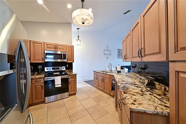 a kitchen with stainless steel appliances granite countertop a stove a sink dishwasher and a refrigerator with wooden floor