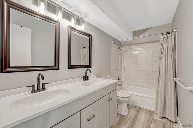 a bathroom with a double vanity sink toilet mirror and shower