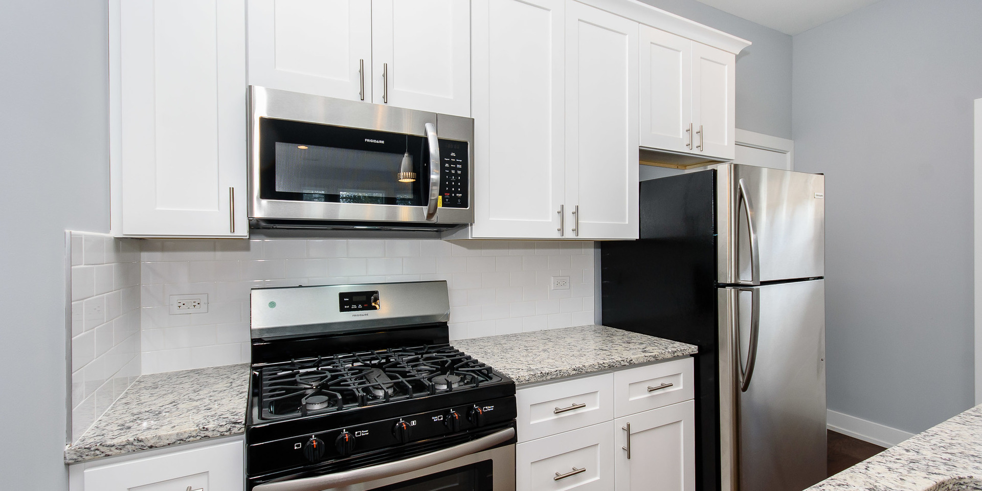 2163 North Bell Avenue, Unit 2F Chicago, IL 60647 - Photo 3 of 12 a kitchen with stainless steel appliances granite countertop a stove a refrigerator and a microwave