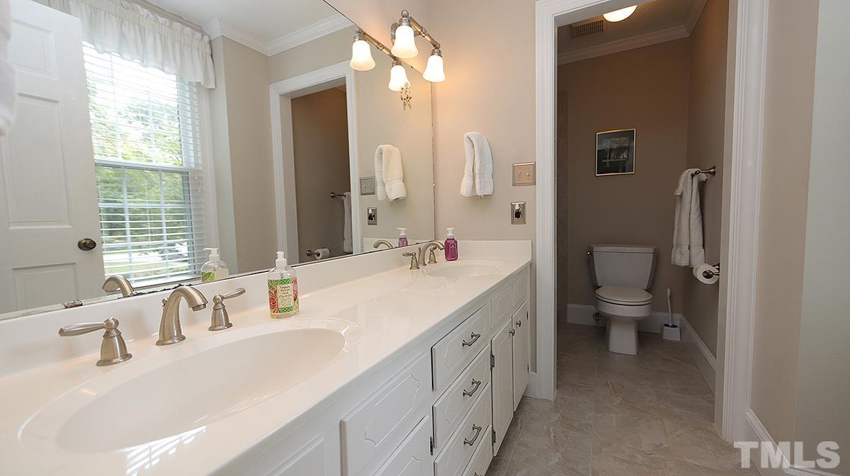 8816 Woodyhill Road Raleigh, NC 27613 - Photo 22 of 30 a bathroom with a double vanity sink toilet and a tub