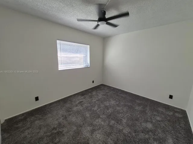 an empty room with a ceiling fan and window