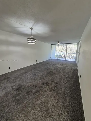 an empty room with chandelier fan and windows