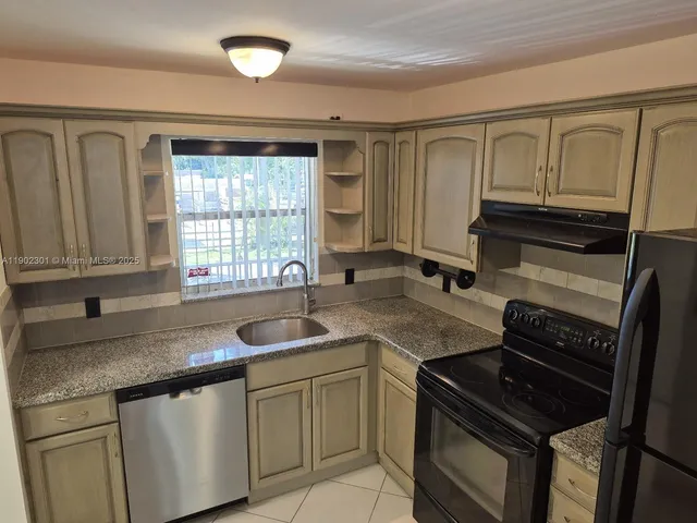 a kitchen with granite countertop a sink stove and cabinets