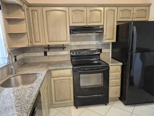 a kitchen with granite countertop a sink stove and refrigerator