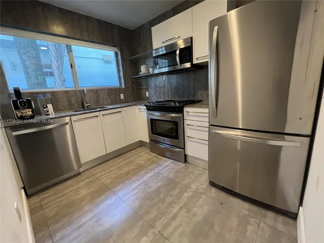a kitchen with stainless steel appliances a refrigerator sink and microwave