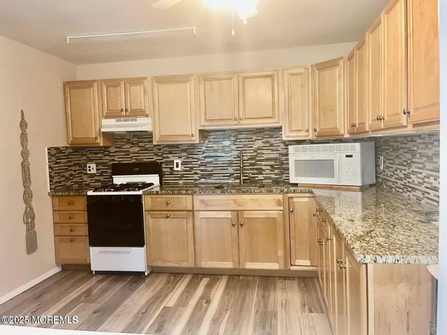a kitchen with stainless steel appliances granite countertop a stove a sink and a white cabinets