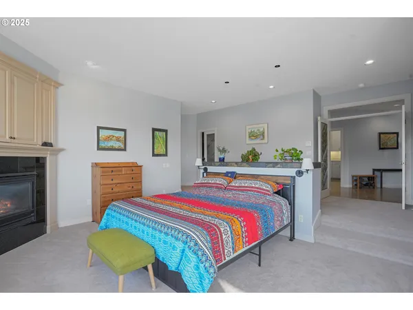 a bedroom with a bed a dresser and a fireplace