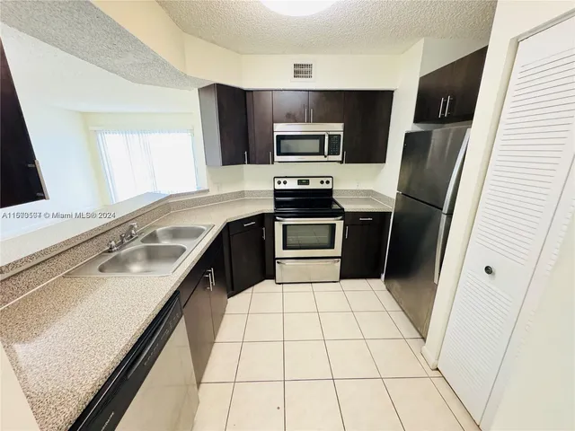a kitchen with a sink a microwave a refrigerator and cabinets