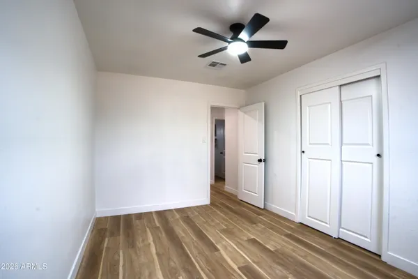 an empty room with wooden floor and ceiling fan