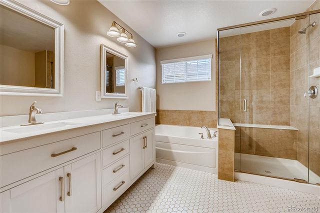 a bathroom with a tub a sink double vanity and a mirror
