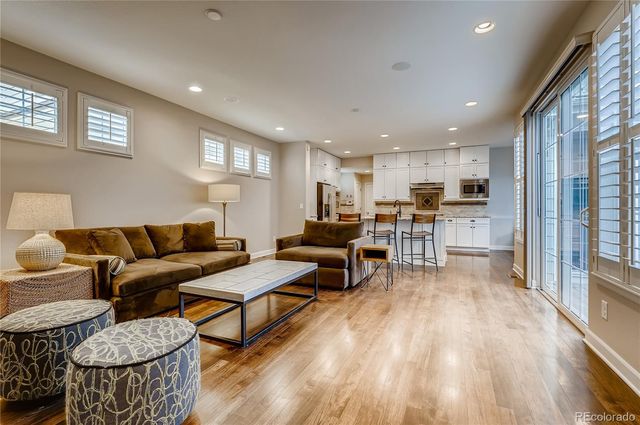 a living room with furniture wooden floor and a kitchen view