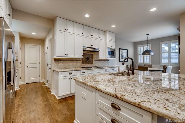 a kitchen with kitchen island granite countertop a sink counter top space appliances and cabinets