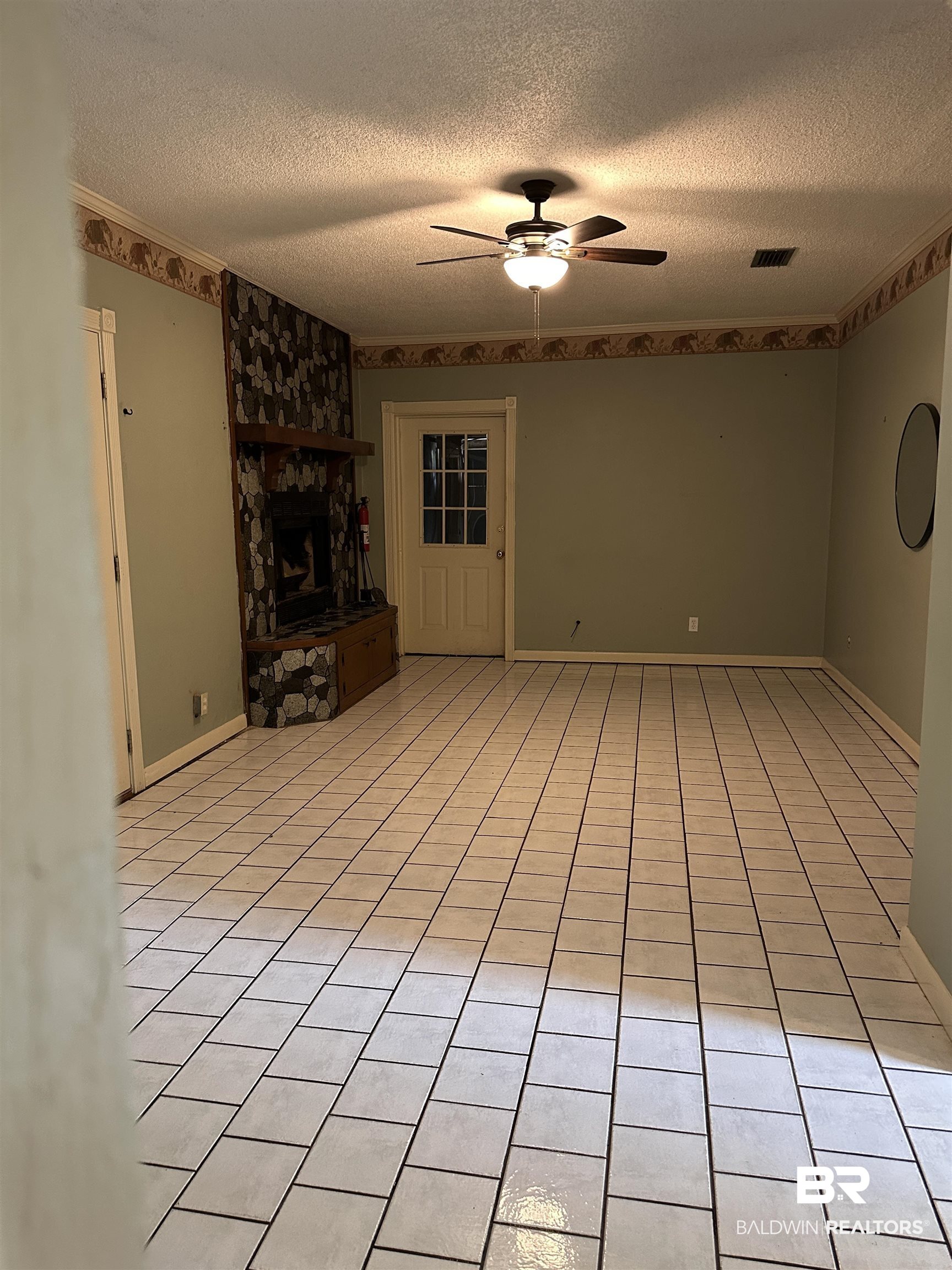 16646 County Road 26 Foley, AL 36535 - Photo 9 of 21 Unfurnished living room featuring light tile patterned floors, ceiling fan, ornamental molding, a textured ceiling, and a stone fireplace