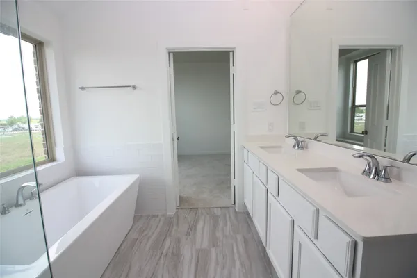 a bathroom with a double vanity sink a mirror and a bathtub