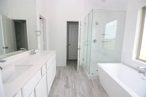 a spacious bathroom with a tub sink and mirror