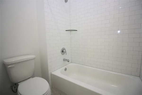 a white toilet sitting next to a bath tub