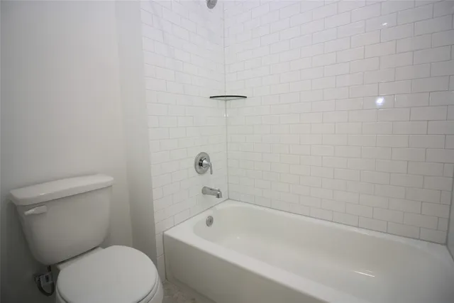 a white toilet sitting next to a bath tub