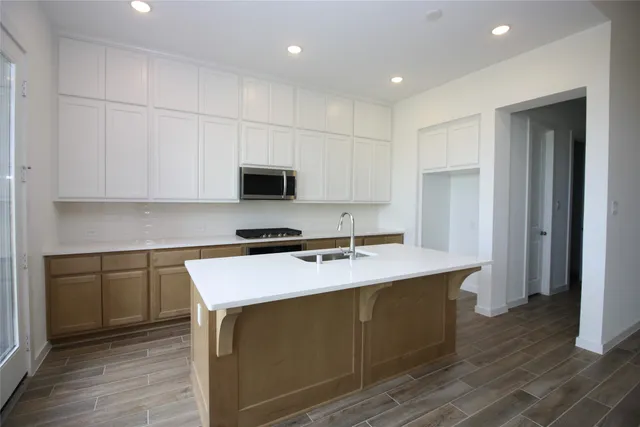 a kitchen with kitchen island stainless steel appliances a sink cabinets and wooden floor