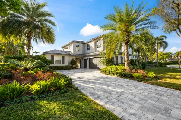 a view of a house with a yard and palm trees