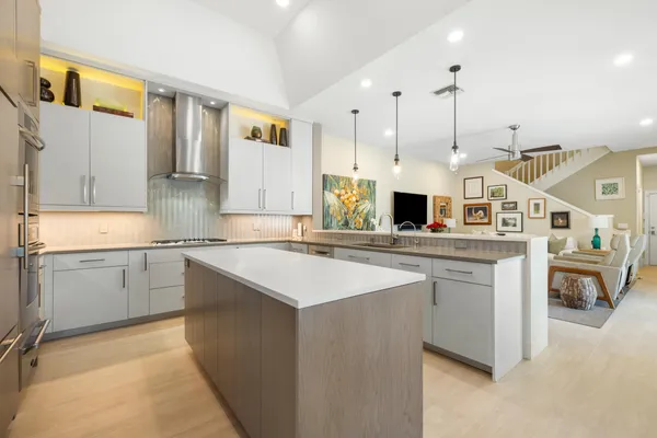 a kitchen with stainless steel appliances kitchen island granite countertop a sink and dishwasher a stove top oven with white cabinets