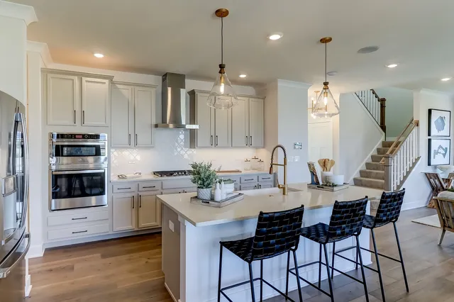 a kitchen with stainless steel appliances kitchen island granite countertop a stove a sink a dining table and chairs