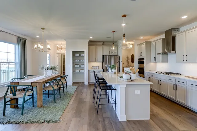 a kitchen with stainless steel appliances kitchen island granite countertop a table chairs sink and cabinets