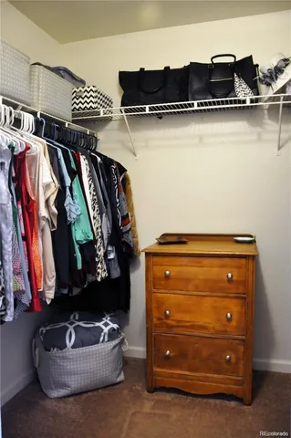 a view of walk in closet with clothes and shoes
