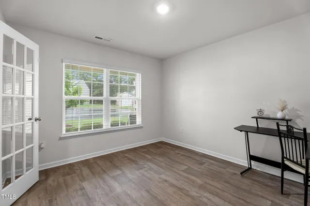 an empty room with wooden floor and windows