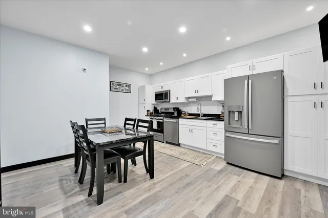 a kitchen with stainless steel appliances granite countertop a refrigerator a stove a microwave oven a sink with island and chairs with wooden floor