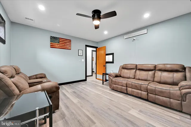 a living room with furniture ceiling fan and a wooden floor