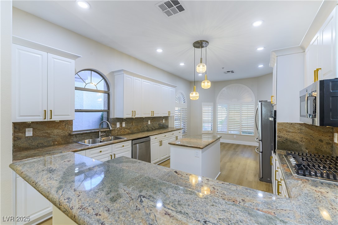 379 Marlin Cove Road Henderson, NV 89012 - Photo 7 of 22 Kitchen with stainless steel appliances, a kitchen island, plenty of natural light, light stone countertops, and recessed lighting