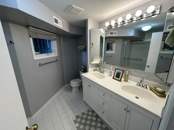 a bathroom with a double vanity sink mirror and toilet