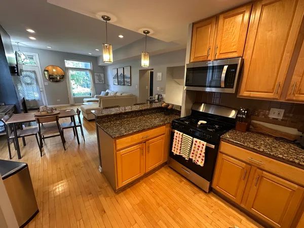 a kitchen with stainless steel appliances granite countertop a stove a sink dishwasher and cabinets with wooden floor