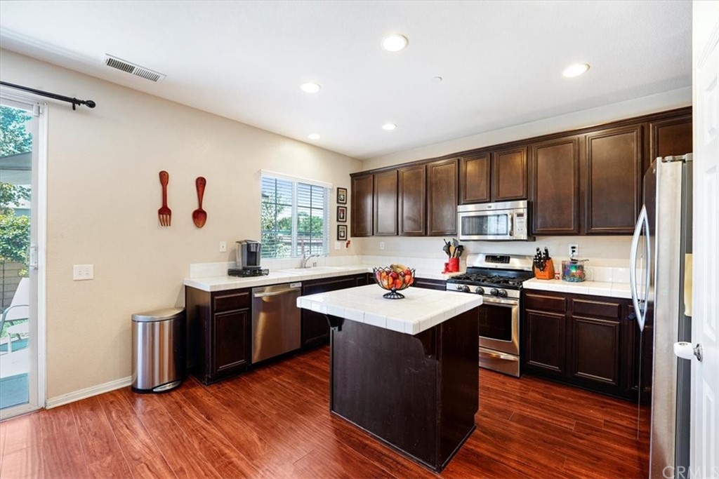 1777 Carrie Way Riverside, CA 92501 - Photo 14 of 35 a kitchen with kitchen island granite countertop a sink appliances cabinets and wooden floor
