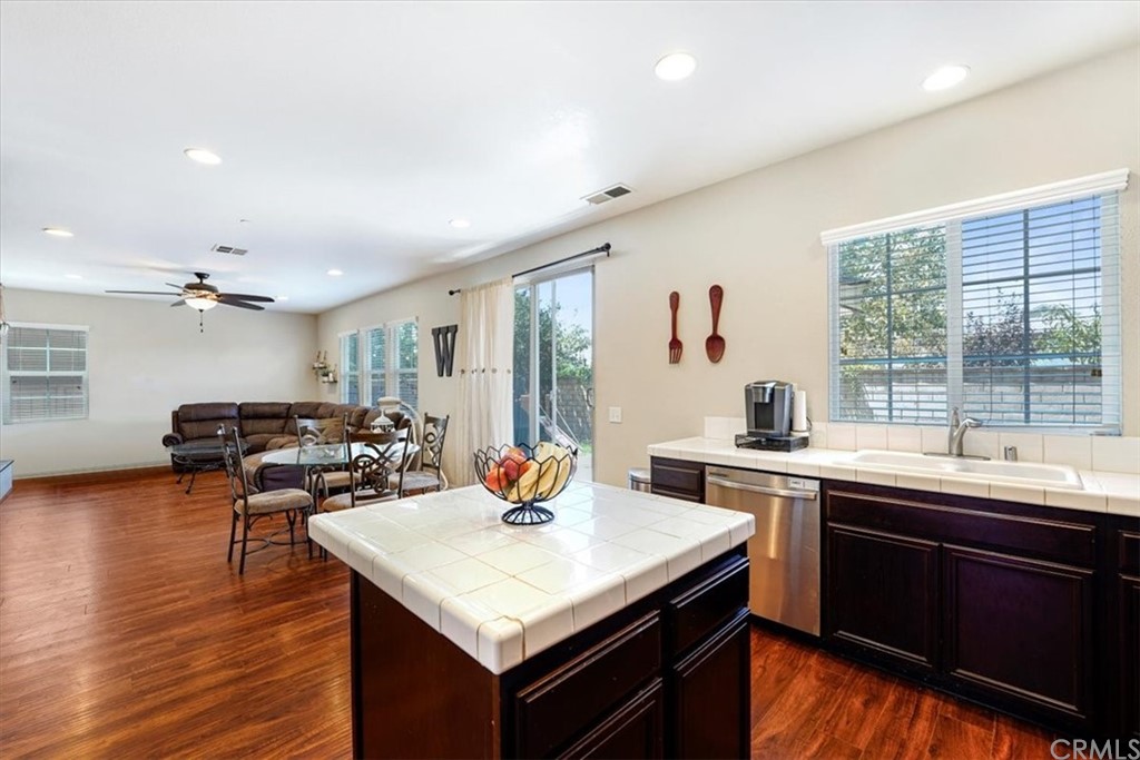 1777 Carrie Way Riverside, CA 92501 - Photo 4 of 35 a kitchen with a stove a sink dishwasher and a dining table with wooden floor